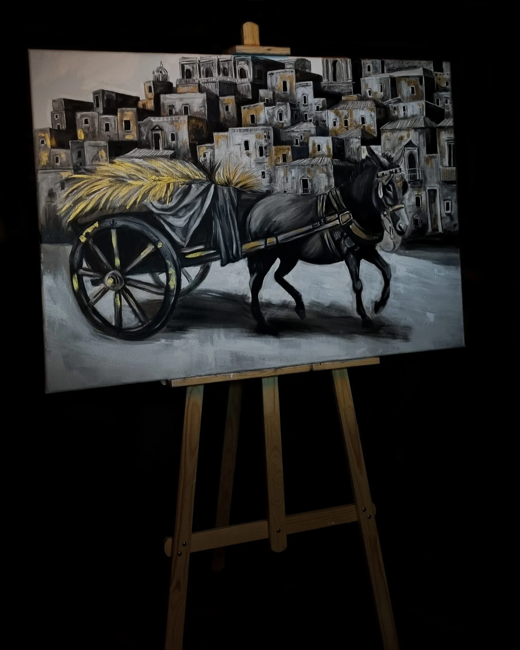 SICILY, 2024 — acrylic on canvas shown on an easel against black: a horse-drawn cart piled with golden wheat before a hillside town
